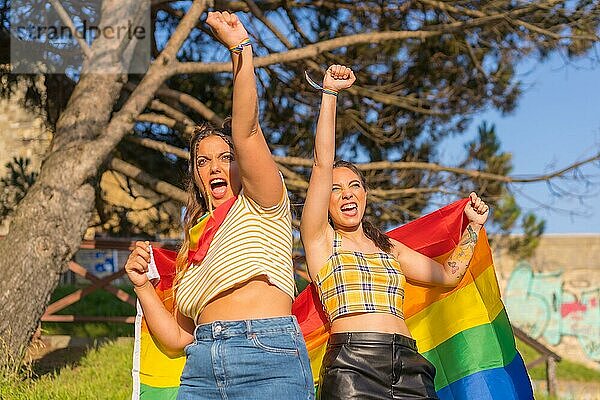 Eine Nahaufnahme von zwei jungen kaukasischen Frauen halten LGBT Stolz Flagge im Freien