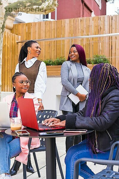 Junge und alternative Geschäftsfrauen schwarzer Ethnie. In einer Teamwork Sitzung  posieren mit Blick in die Kamera