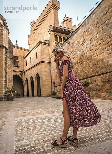 Porträt einer blonden Frau in einer mittelalterlichen Burg  die ein rotes Kleid trägt und sich amüsiert