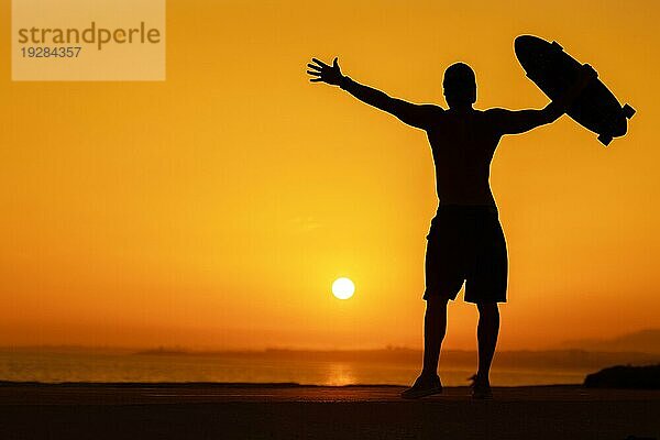 Silhouette eines freien Mannes mit einem Skateboard bei hellem Sonnenuntergang. Mittlere Aufnahme