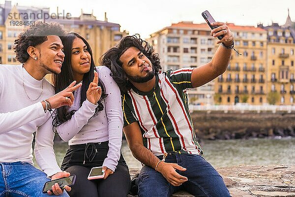 Lifestyle  drei schwarze Freunde  die Spaß haben und ein Selfie machen. Afrohaar Junge  Brünette Junge mit langen Haaren und Brünette Mädchen