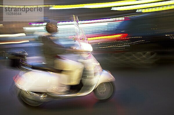 Abstraktes  verschwommenes Bild eines nachts fahrenden Motorrollers