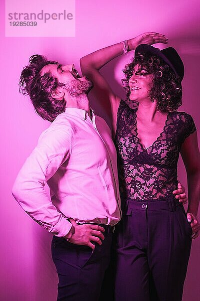 Studio Lifestyle  ein junges  verliebtes Paar  das sich am Valentinstag amüsiert  beleuchtet von einem rosa Neonlicht