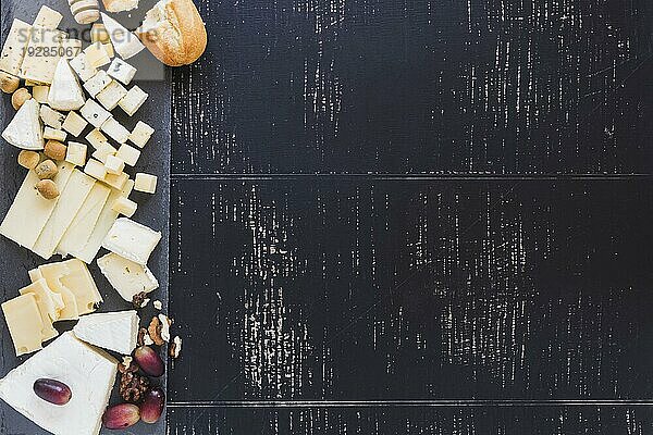 Overhead Ansicht Brot mit verschiedenen Arten von Käse mit Trauben schwarz strukturierten Hintergrund