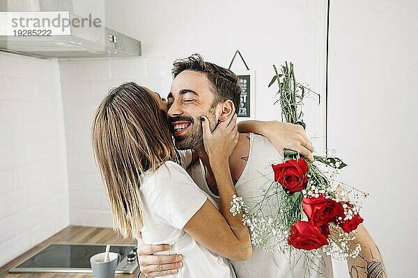 Frau umarmt Mann nach Erhalt eines Blumenstraußes