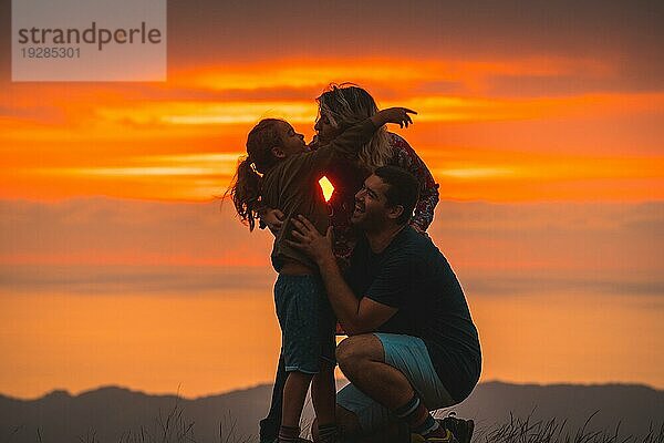 Eine Familie  die sich auf dem Gipfel eines Berges bei Sonnenuntergang umarmt und Spaß hat. Abenteuer Lebensstil Ein Sommernachmittag in den Bergen des Baskenlandes