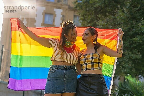 Eine Nahaufnahme von zwei jungen kaukasischen Frauen halten LGBT Stolz Flagge im Freien