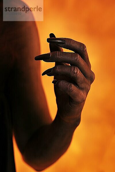 Weibliche Hand mit schwarzer Körperbemalung und künstlichen Fingernägeln
