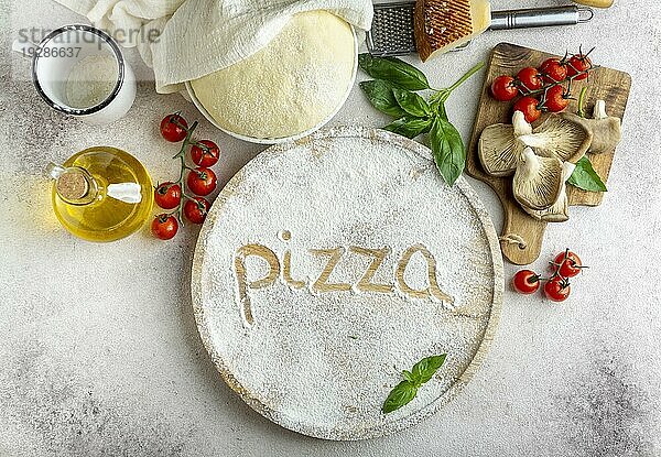 Draufsicht Pizzateig mit Champignons Tomaten Wort geschrieben Mehl