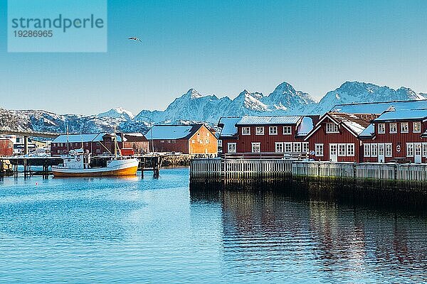 Alte traditionelle Fischerhütte namens Rorbu bei Svolvaer auf den Lofoten in Norwegen im Winter mit Schnee an einem klaren Tag mit blauem Himmel