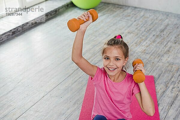 Portrait lächelndes Mädchen beim Training mit orangefarbener Hantel