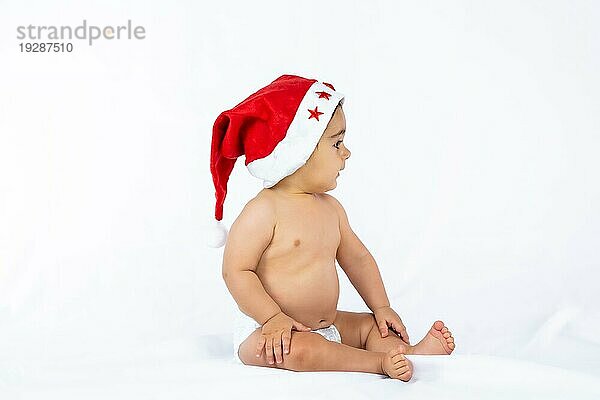 Ein kleiner Junge mit einer roten Weihnachtsmütze auf weißem Hintergrund  Kopierraum  Blick nach rechts