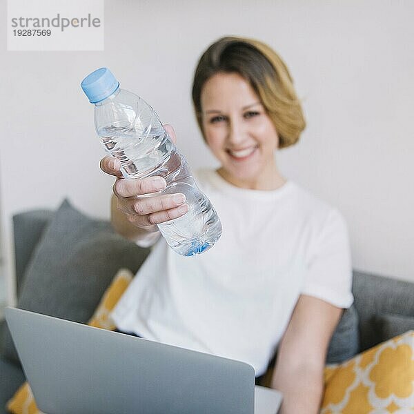 Unscharfe Frau mit Laptop und Wasserflasche