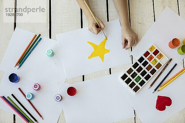 Draufsicht Mädchen malen gelben Stern mit Pinsel weißes Papier