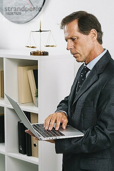 Portrait reifer männlicher Anwalt mit Laptop
