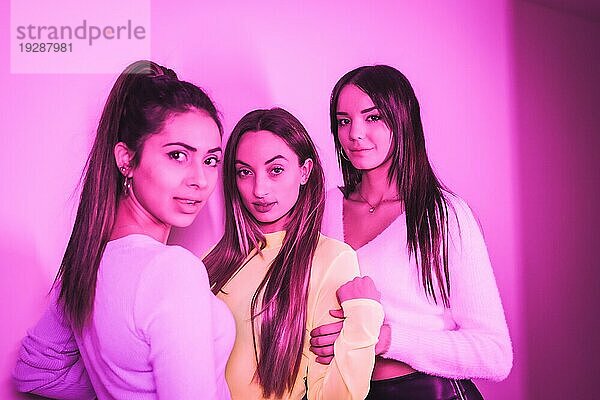 Lebensstil von Freunden  die in einem Nachtclub mit rosa Neonlicht feiern  Porträt einer jungen  schönen kaukasischen Frau  die in die Kamera schaut