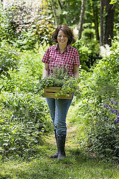 Junge Frau mit Kräutern im Garten  junge Frau mit Kräutern in einem Garten