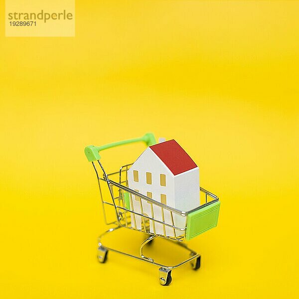 Close up Haus Modell Miniatureinkaufswagen gegen gelben Hintergrund