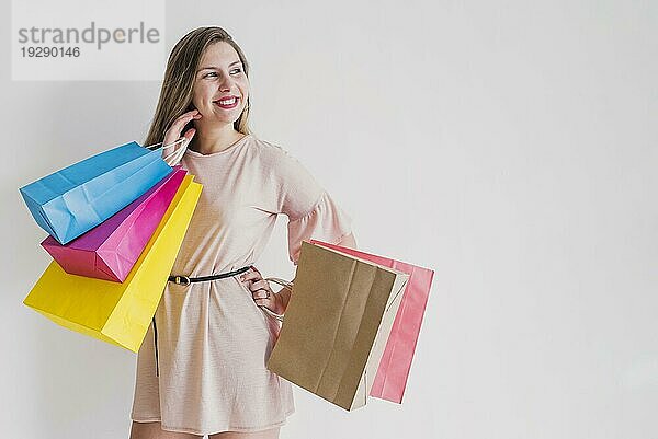 Glückliche Frau mit leuchtenden Einkaufstaschen stehend