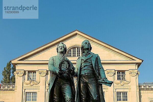 Goethe Schiller Denkmal in Weimar im morgendlichen Sonnenlicht unter blauem Himmel