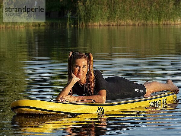 Frau liegt entspannt auf standup paddle board im See  Deutschland  Europa