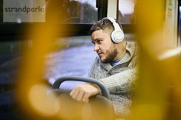 Mann mit Kopfhörern auf einer Busfahrt
