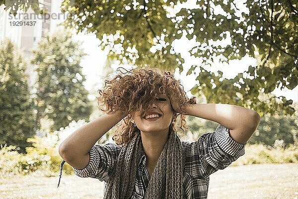 Fröhliche Frau mit zerzausten Haaren im Park