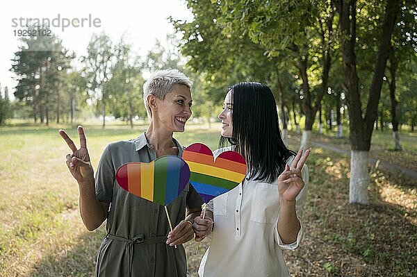 Lesbisches Paar  das eine Flagge in Form eines lgbt Herzens hält