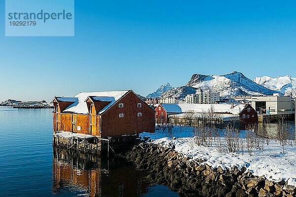 Alte traditionelle Fischerhütte namens Rorbu bei Svolvaer auf den Lofoten in Norwegen im Winter mit Schnee an einem klaren Tag mit blauem Himmel