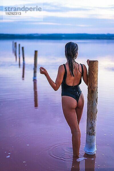 Eine junge Brünette Kaukasierin im Urlaub in der rosa Lagune von Torrevieja  genießt den Sommer im Wasser mit einem schwarzen Badeanzug  Alicante. Spanien