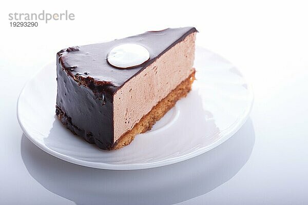 Leckerer Schokoladenkuchen auf dem Teller auf weißem Hintergrund. Unscharfer Fokus