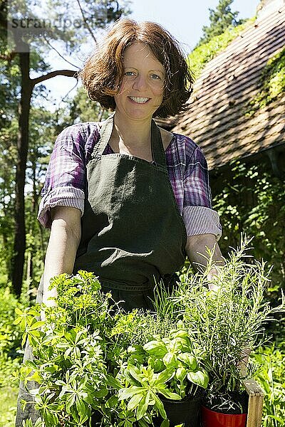 Frau mit Kräutern im Korb im Garten  woman with herbs in a basket in a garden