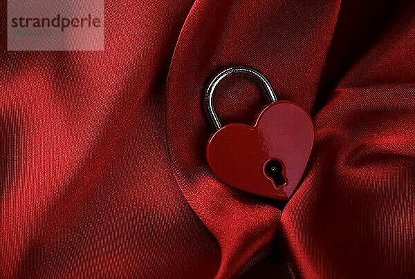 Herzförmiges Vorhängeschloss auf rotem Seidenhintergrund. Valentinstag Konzept. Symbol der Liebe  Kopie Raum