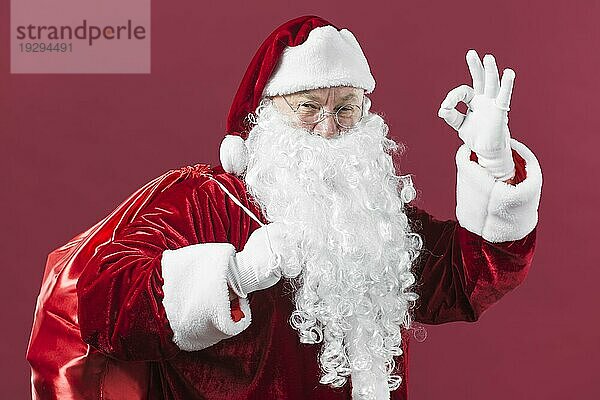 Weihnachtsmann mit Sack zeigt okay Geste