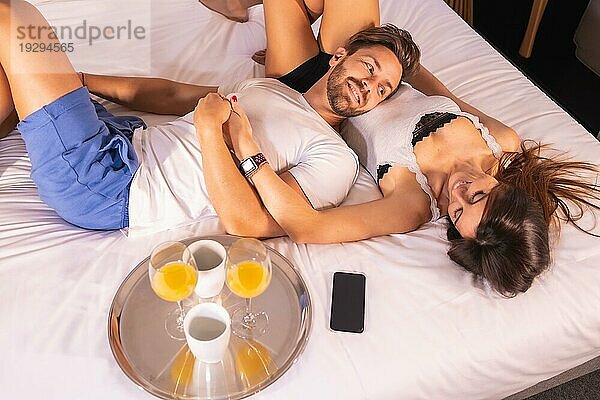 Ein verliebtes Paar im Schlafanzug beim Frühstück im Hotelbett  Lebensstil eines verliebten Paares. Foto von oben