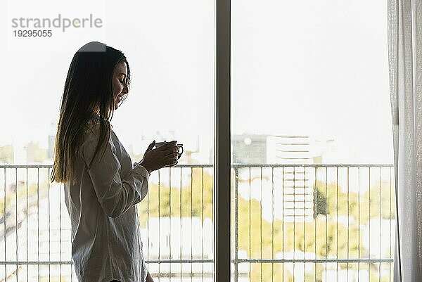 Portrait glückliche Frau stehend Balkon hält Kaffeetasse Hand