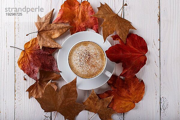 Heißer Kaffee Cappucino und Herbstblätter auf alten weißen hölzernen Hintergrund.saisonale entspannen Konzept