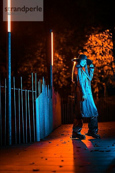 Mädchen mit Hut geht nachts in einem Park spazieren  nachdenklich und genießt die Ruhe ohne Menschen  blaues Licht