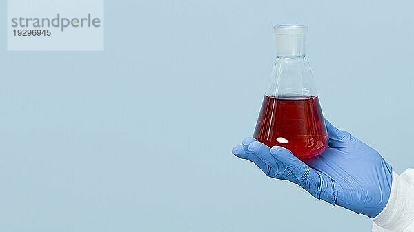 Vorderansicht eines Wissenschaftlers  der eine rote Chemikalie mit Kopierraum hält