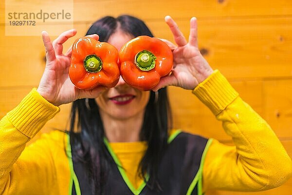 Ein brünettes kaukasisches Obstmädchen  das in einem Gemüseladen arbeitet  hat Spaß an roten Paprika in der Hand