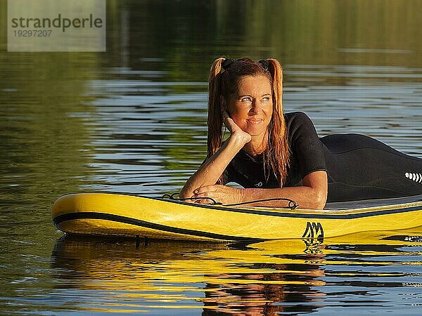 Frau liegt entspannt auf standup paddle board im See  Deutschland  Europa