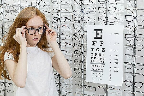 Attraktive junge Frau mit Brille steht ordentlich snellen chart optica