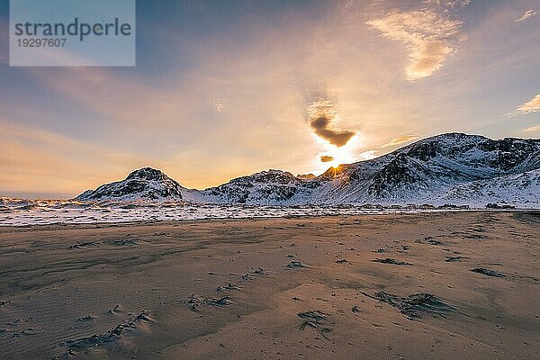 Blick über den Sandstrand in der Nähe des Dorfes Fredvang bei einer Wanderung in Ytresand auf der Inselgruppe der Lofoten in Norwegen im goldenen Licht des Sonnenuntergangs an einem klaren Wintertag