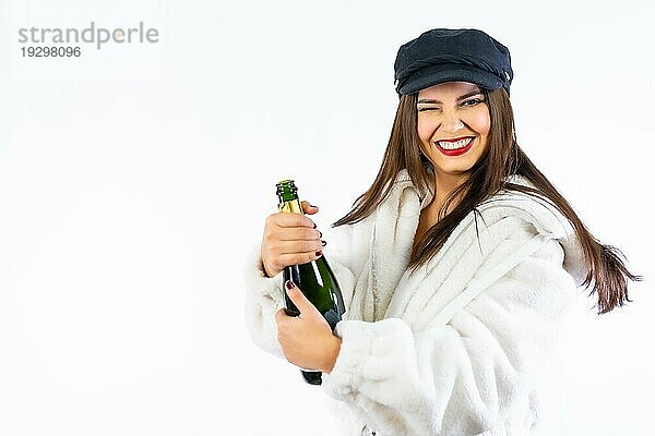 Junges lateinamerikanisches Mädchen  das Silvester auf einem weißen Hintergrund feiert. Öffnen einer Flasche Champagner sehr lächelnd