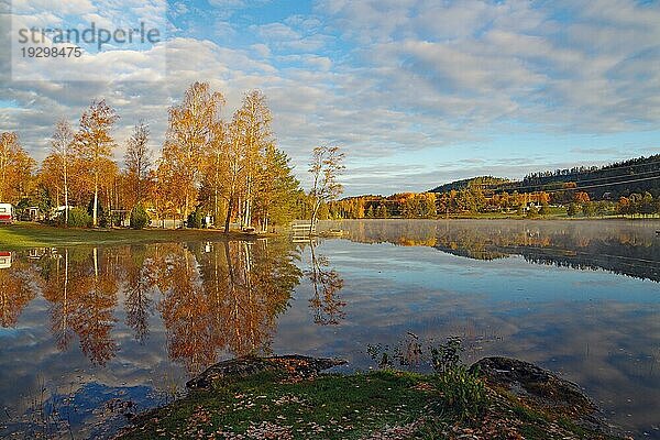 Steg  Bäume und Häuser spiegeln sich an einem ruhigen Herbstmorgen im Wasser des Bullaren  See  Oktober  Bohuslän  Schweden  Europa