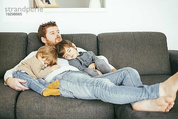 Papa macht Mittagsschlaf mit Söhnen auf dem Sofa