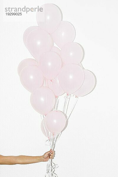 Close up Hand hält Bündel rosa Luftballons vor weißem Hintergrund