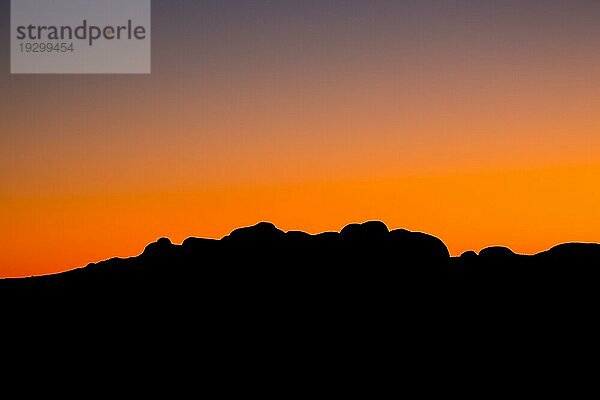 Die Silhouette der Felsblöcke der Olgas bei Sonnenuntergang an einem klaren Winterabend im Northern Territory  Australien  Ozeanien