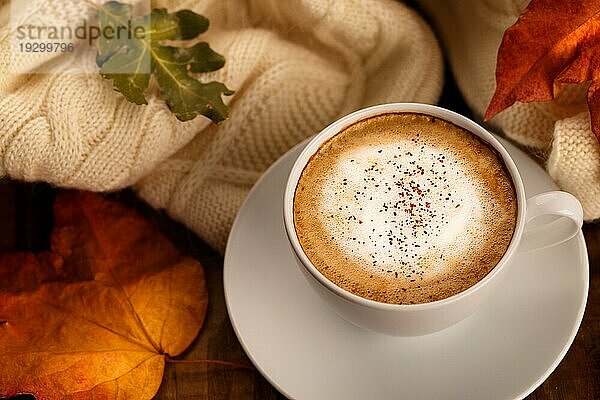 Heißer Kaffee Cappucino  Decke und Herbstblätter auf alten hölzernen Hintergrund. Saisonale entspannen Konzept