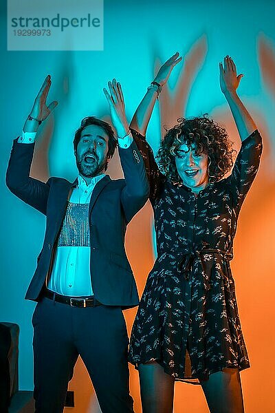 Party Lebensstil  ein sehr glückliches Paar tanzen beobachten den Tanz auf einem Telefon auf einer Party mit blauen und orangefarbenen Lichtern